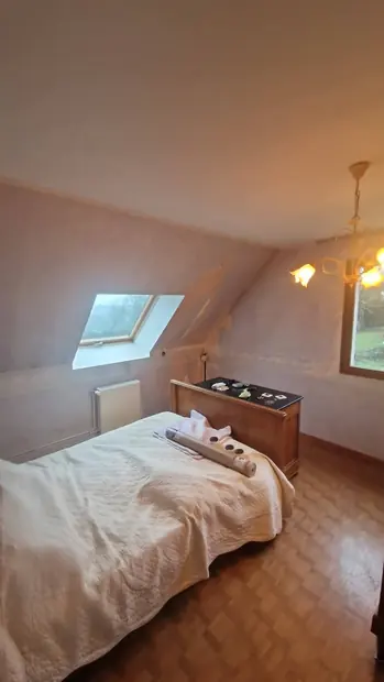 Chambre sous combles, murs clairs et fenêtre de toit